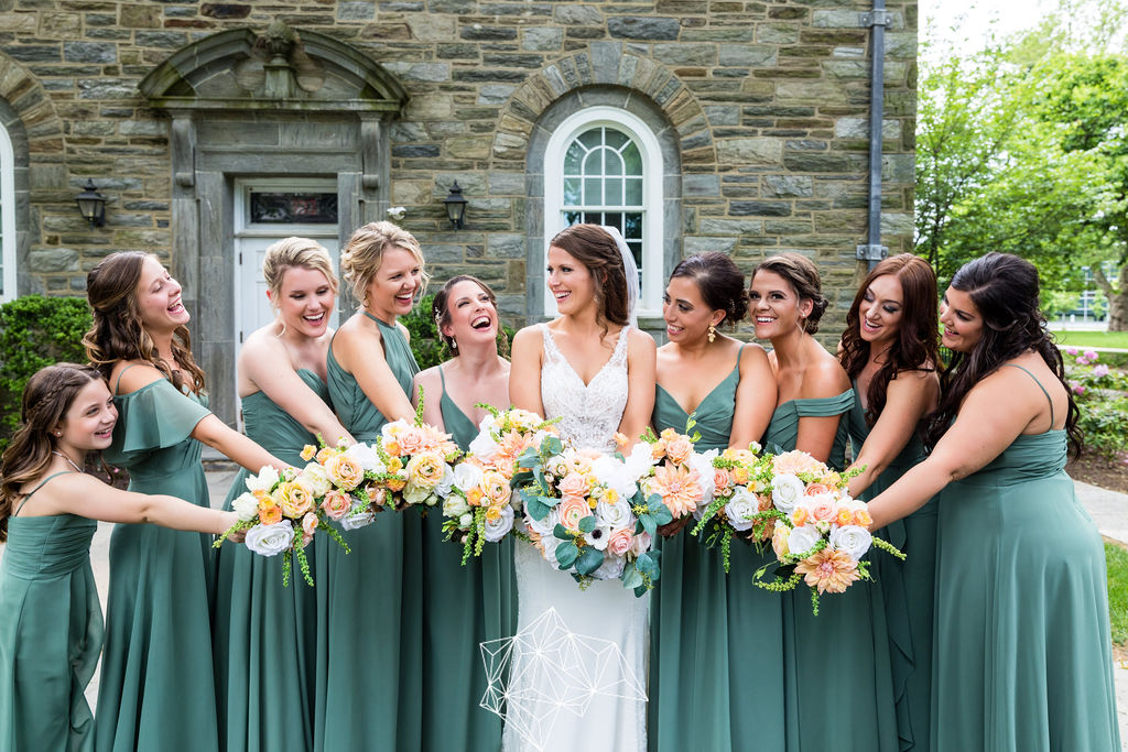 Bride and bridesmaids in sage green gowns holding peach, coral, and white faux bouquets, Ballroom at Ellis Preserve wedding Delaware County Pennsylvania